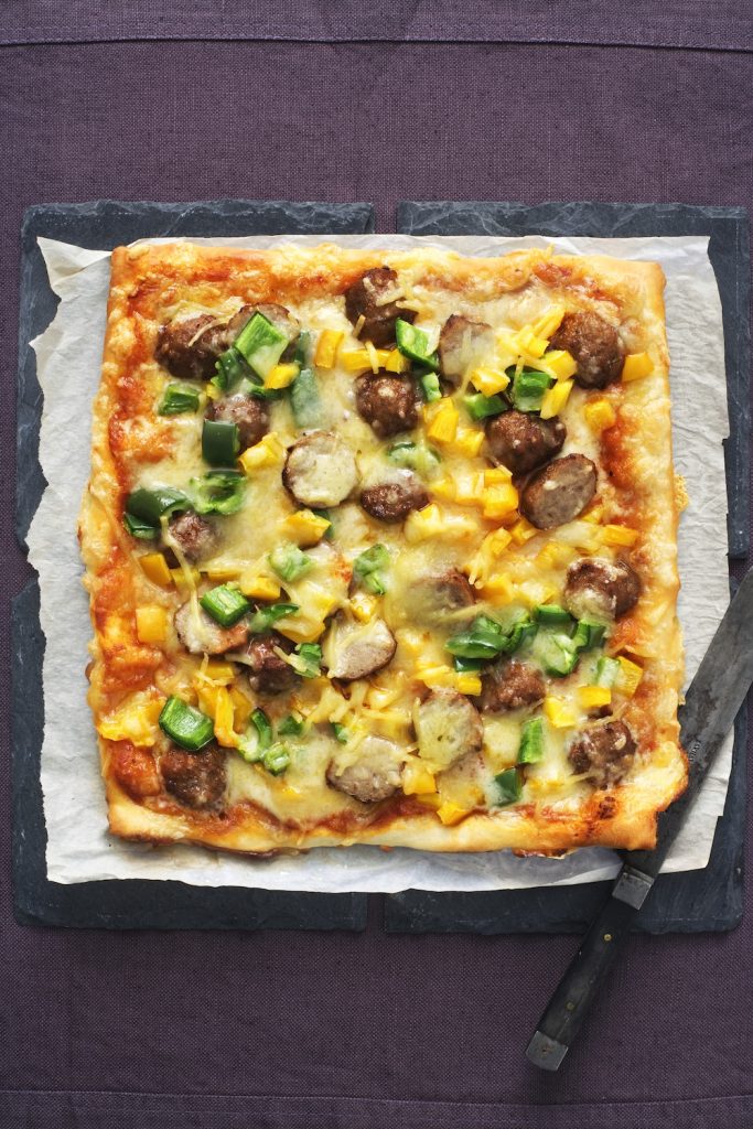 Pizza med köttbullar på svart uppläggningsfat