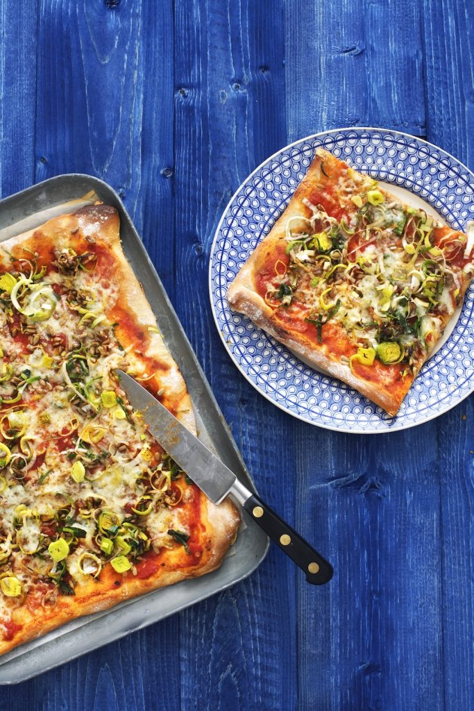 Pizza med purjolök på blått träbord