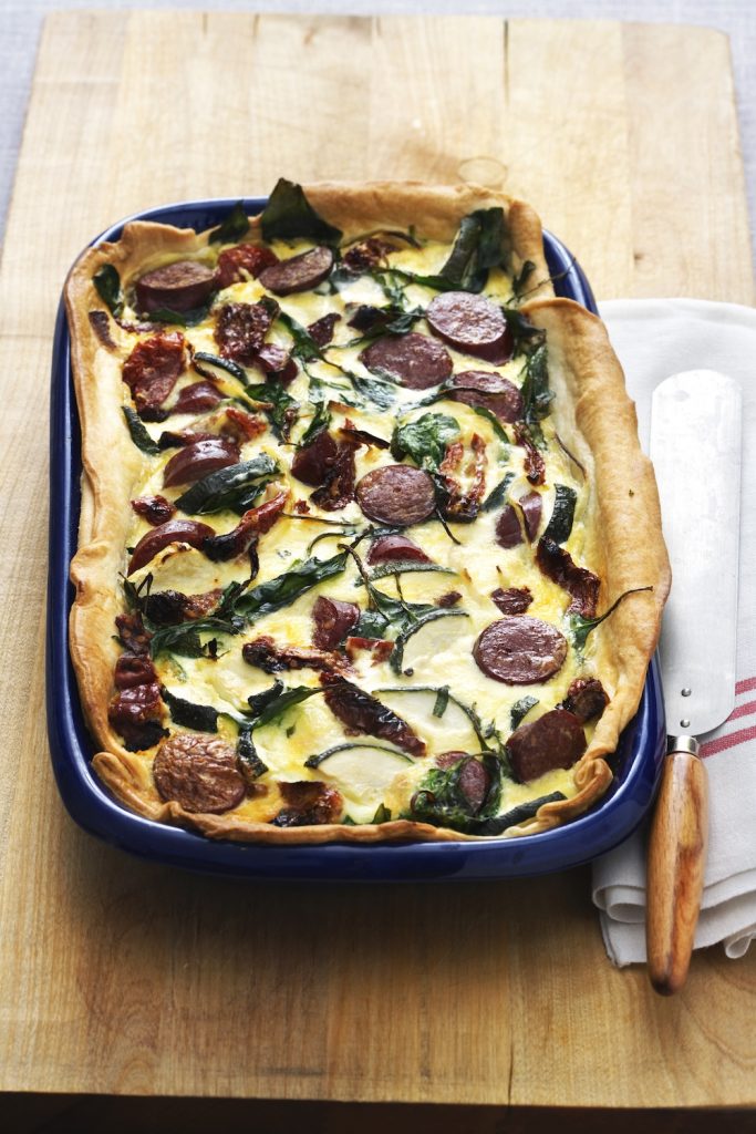 Paj med lammkorv och spenat serverat i blå ugnsform