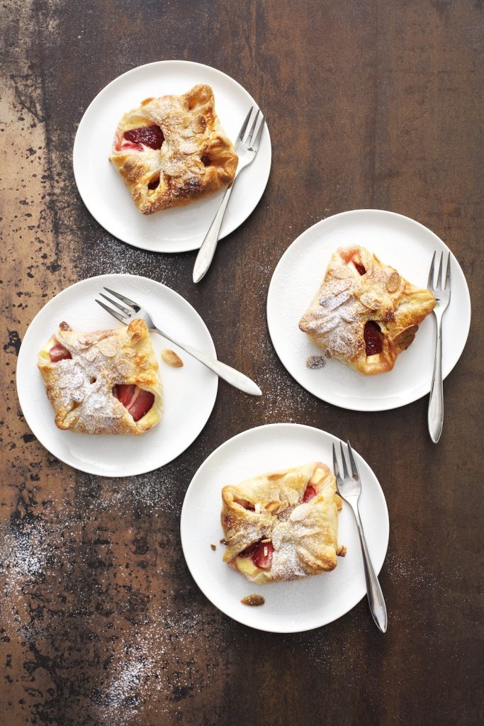 Smördegsknyten med bär och vaniljcreme, pudrade med florsocker. Serveras på fat med gaffel.