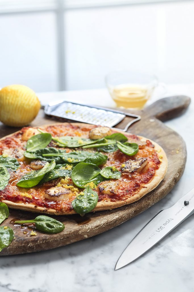 Tunn pizza med färsk spenat, olivoja och riven citron