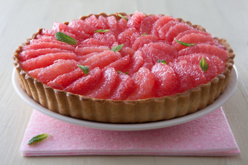 Avokado och grapefruktpaj med krabbkött, serverat på ett vitt uppläggningsfat toppat med mynta