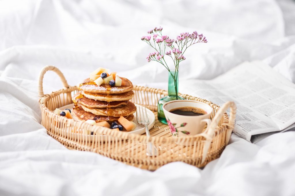 En hög med pannkakor vackert uppdukat i en korg på sängen.