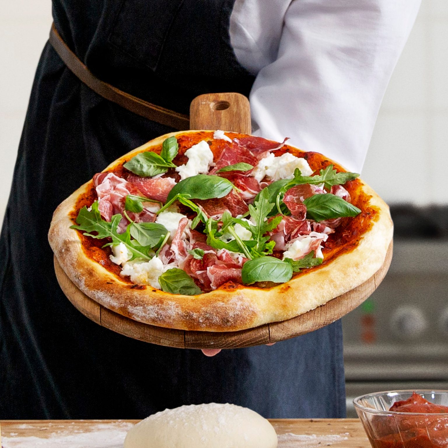 En kock håller en härlig nybakad pizza på en bricka i handen
